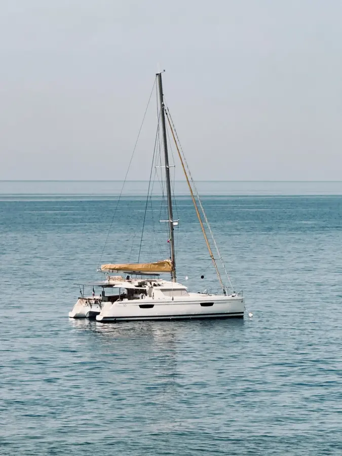 Un catamarano bianco all'ancora su un mare calmo e chiaro