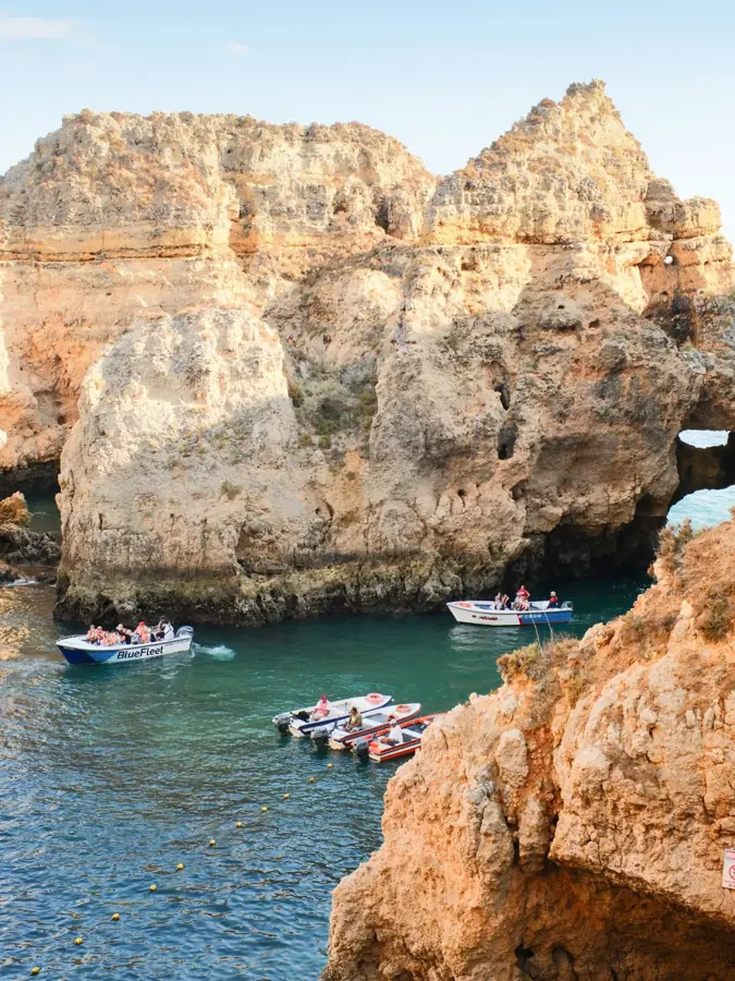 Piccole barche tra i pilastri di roccia dorata davanti a Lagos