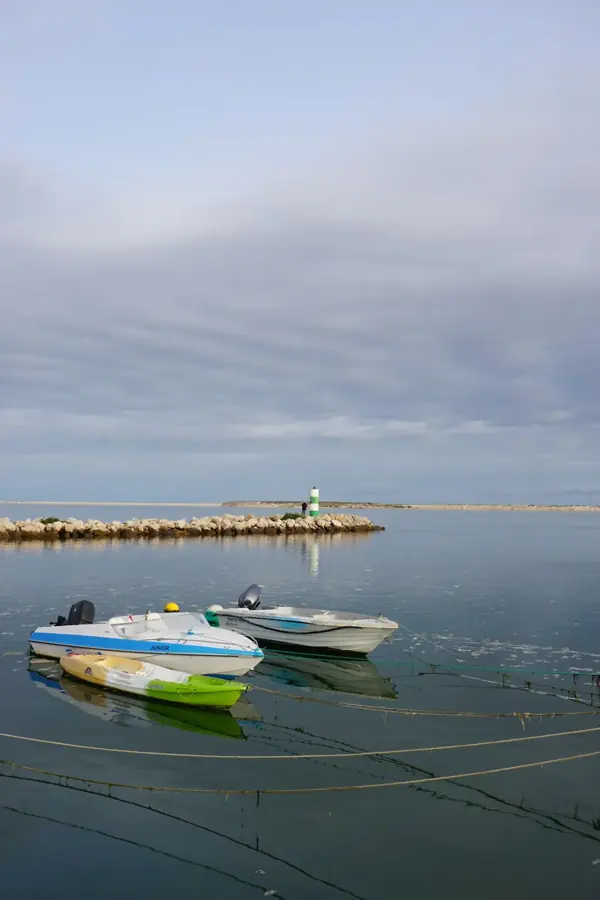 Barche ormeggiate nell'acqua calma davanti alla Fuzeta