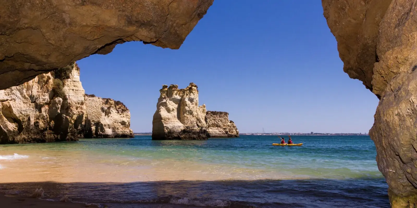 Faraglioni di Lagos visti attraverso un arco di roccia, un kayak sull'acqua