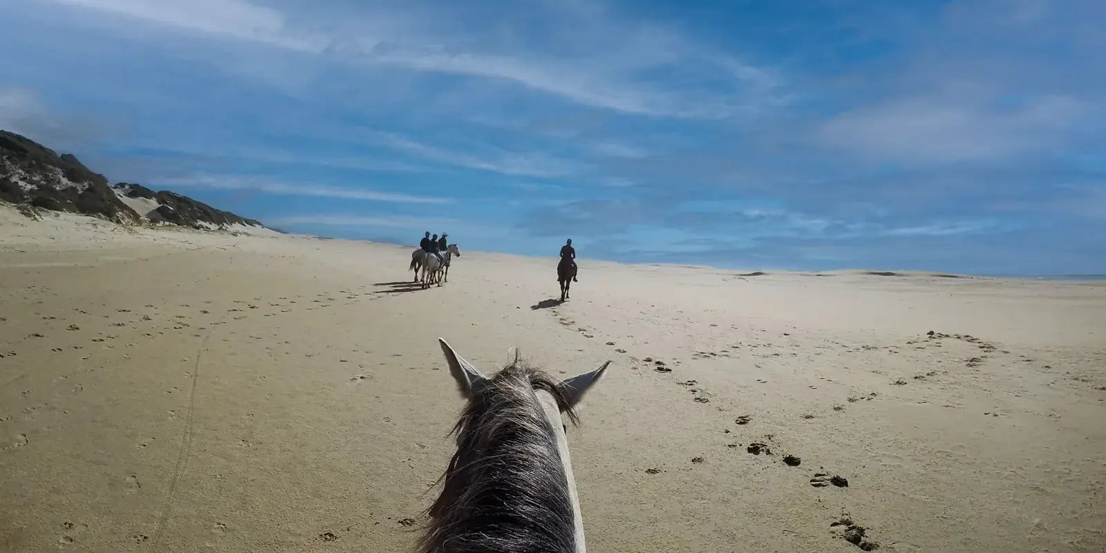 A cavallo su una spiaggia ampia e deserta, con le dune sullo sfondo
