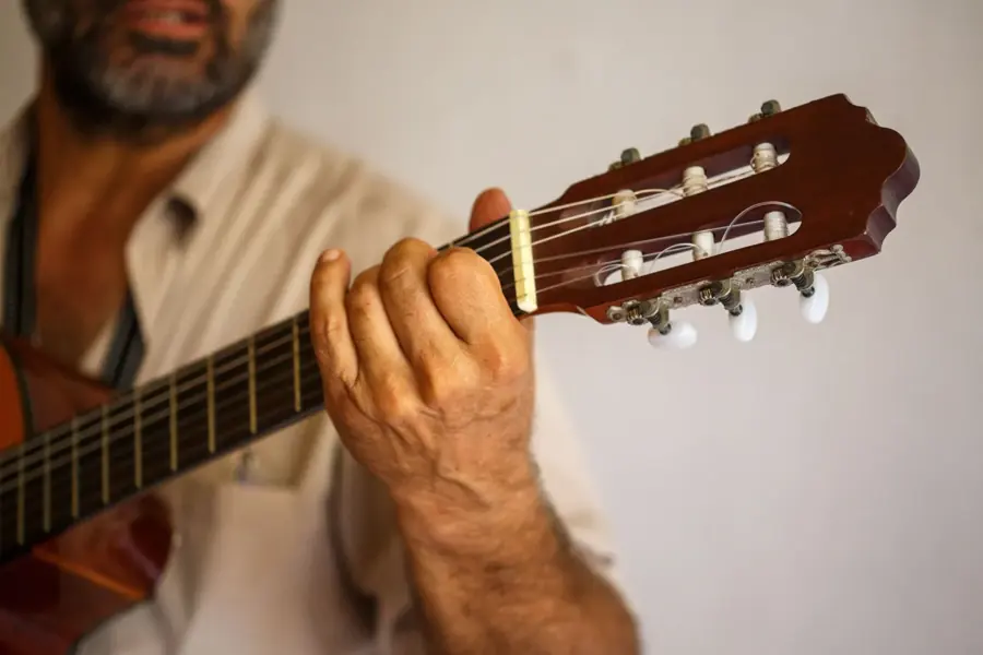 Le mani di un musicista su una chitarra di legno