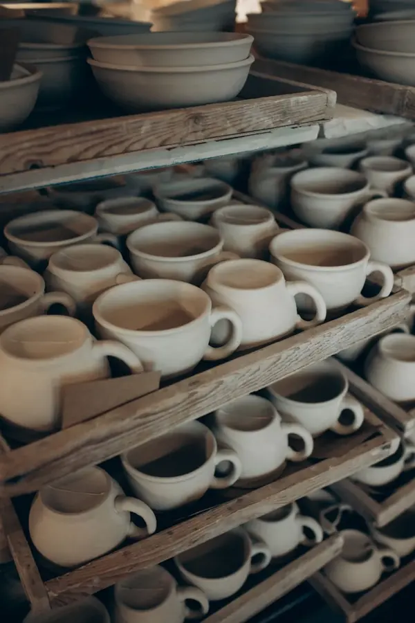 Tazze e ciotole di ceramica fatte a mano su scaffali di legno