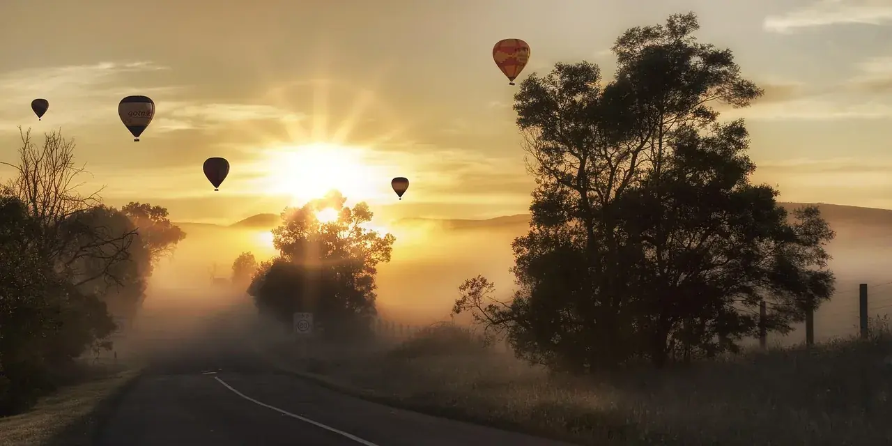 Mongolfiere nel cielo all'alba sopra una strada di campagna nella nebbia