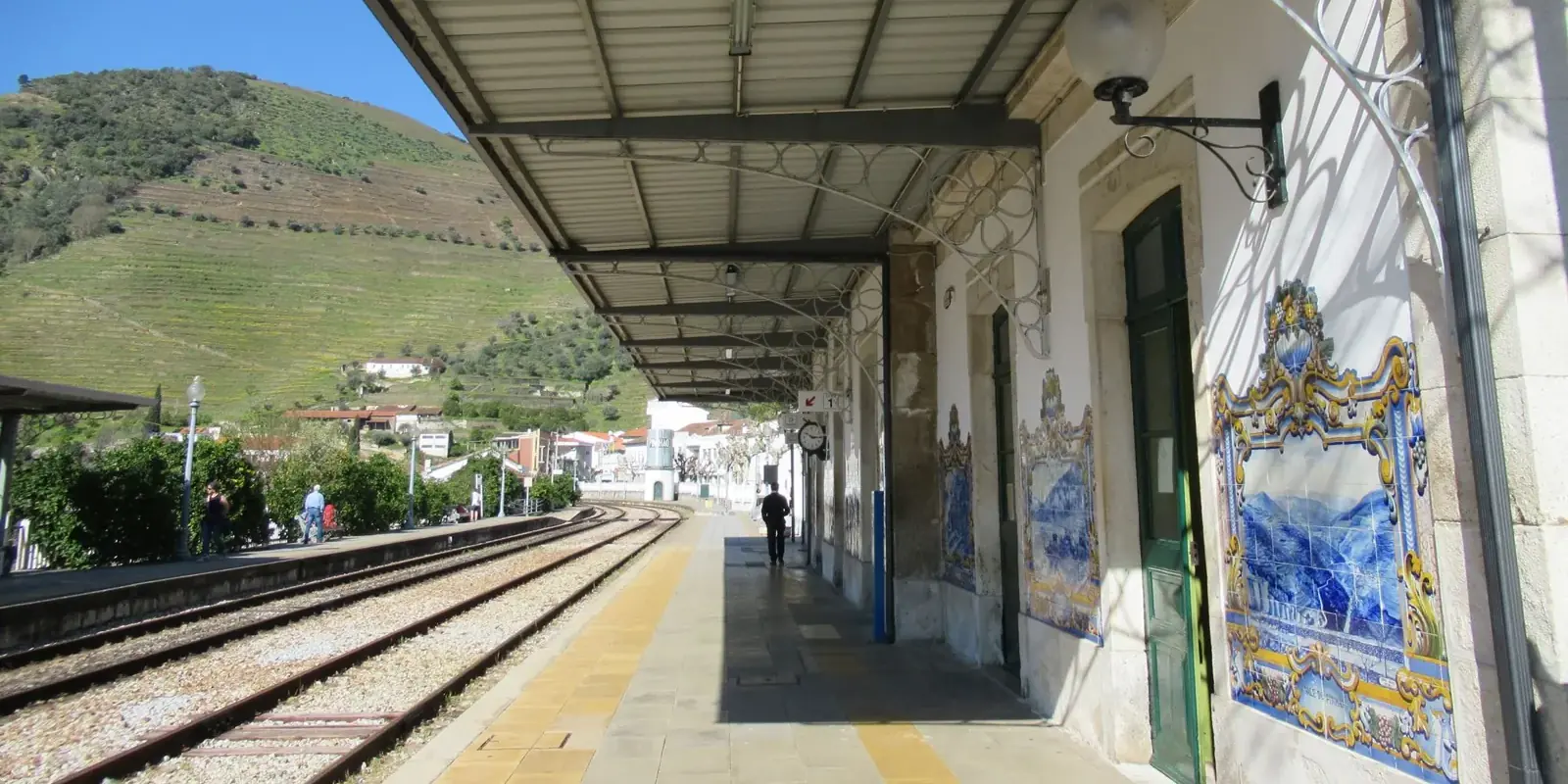 Il binario di una stazione del Douro decorata con pannelli di azulejos, vigne sulla collina