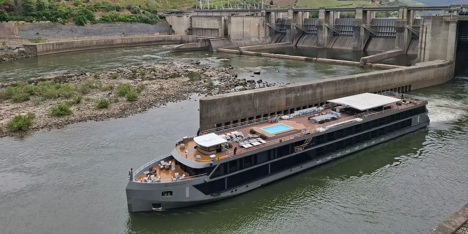 Una nave fluviale attraversa la chiusa di una diga sul Douro, colline verdi intorno