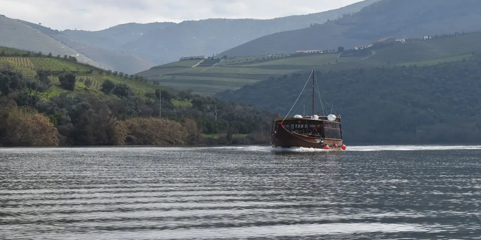 Una barca rabelo naviga sul Douro tra colline coperte di vigne