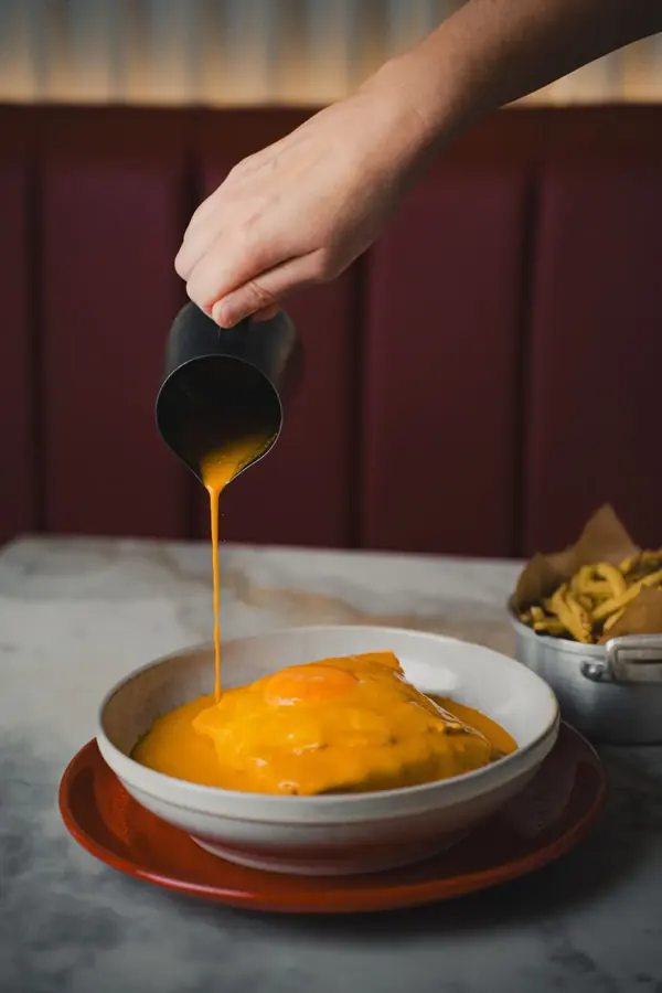 La salsa versata su una francesinha, il piatto simbolo di Porto