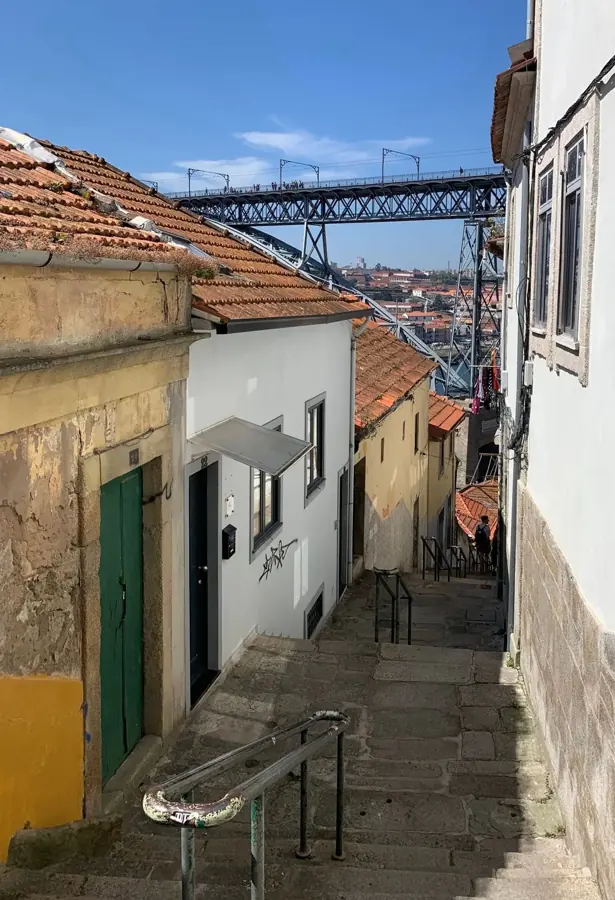 Una scalinata di pietra tra vecchie case di Porto, con il ponte Dom Luís I sullo sfondo