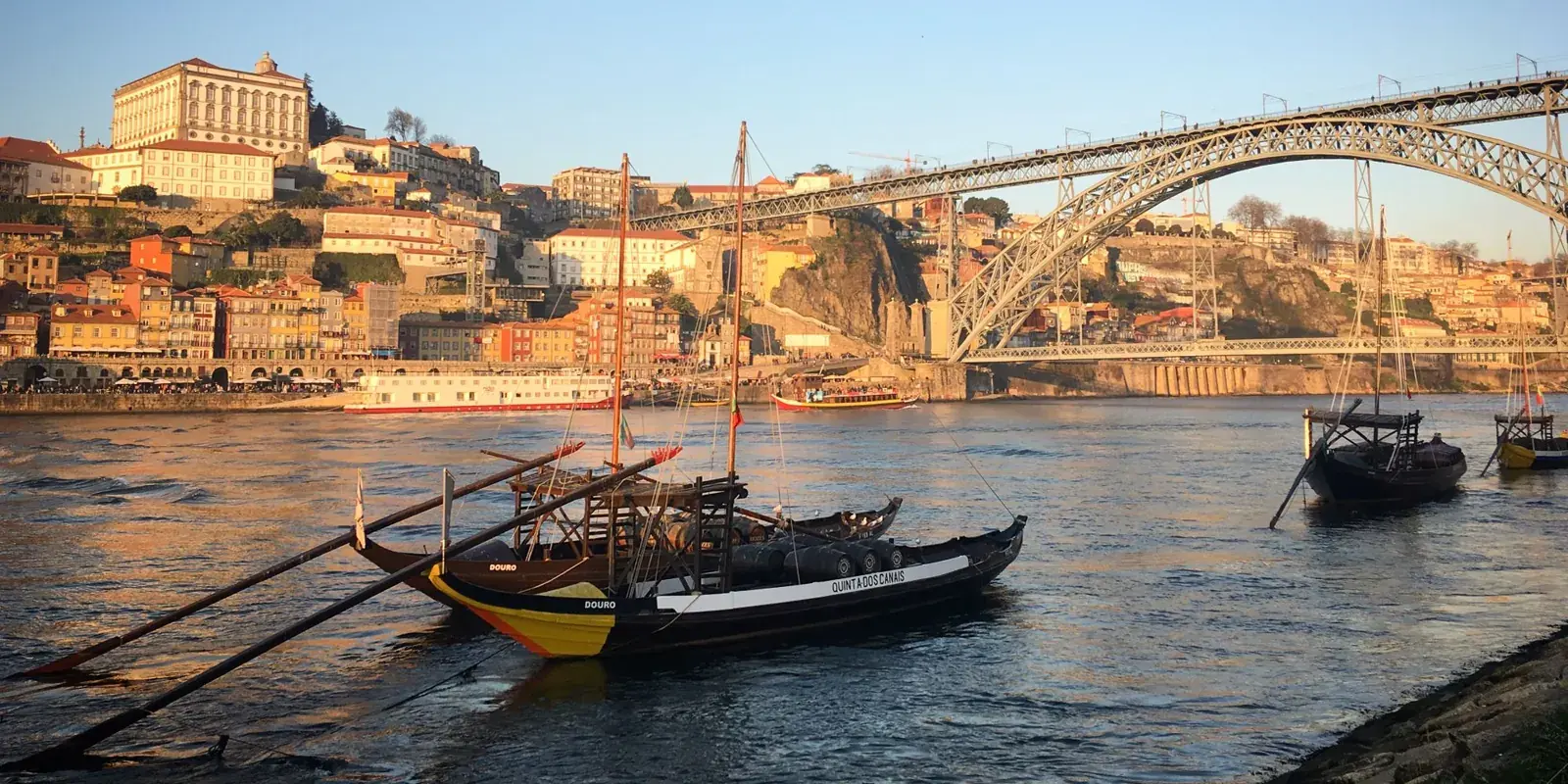 Barche rabelo sul Douro nella luce del tardo pomeriggio, con il ponte Dom Luís I e la Ribeira di Porto