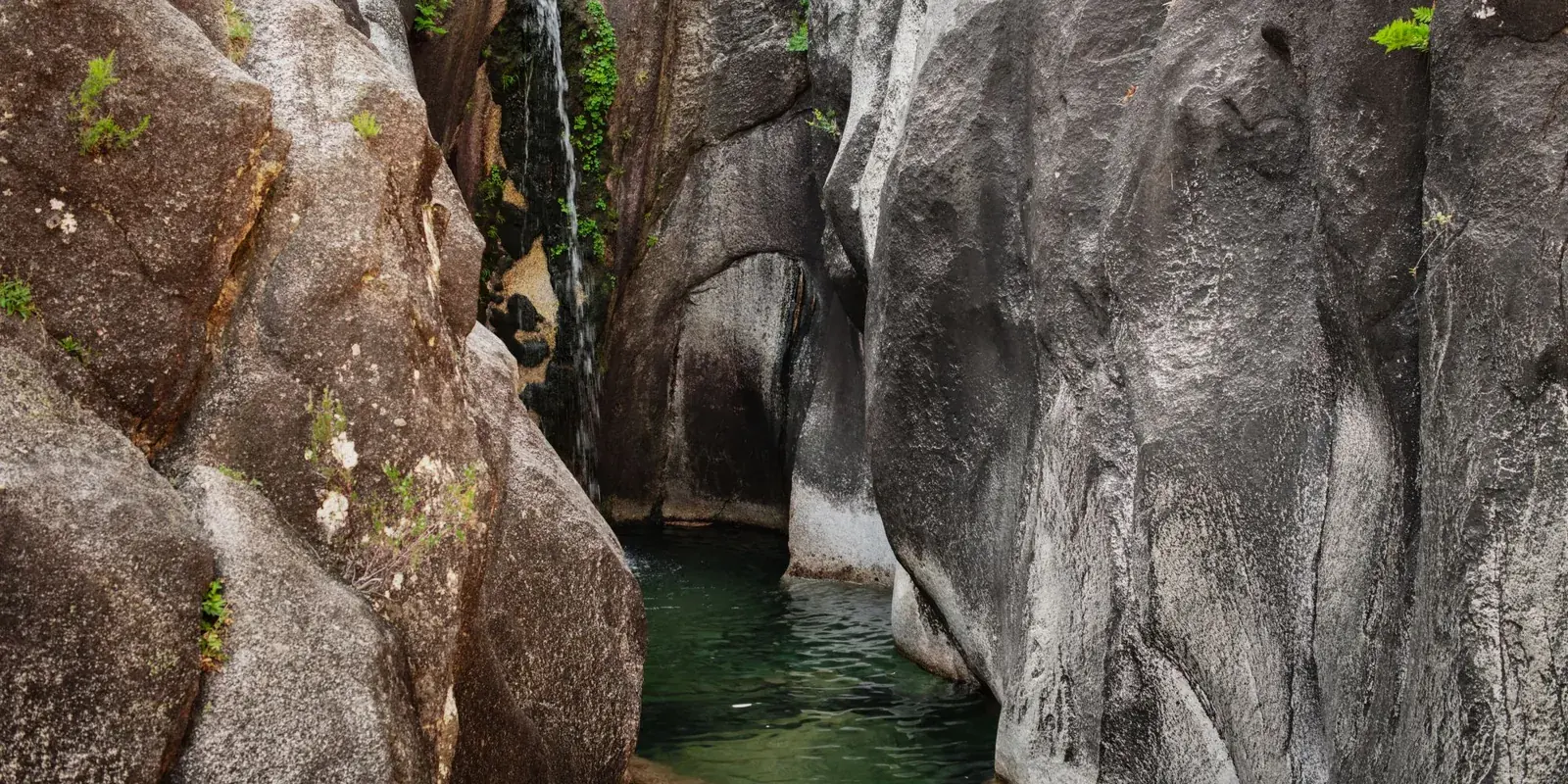 La cascata do Arado tra le rocce di granito del Gerês, con la pozza verde ai piedi